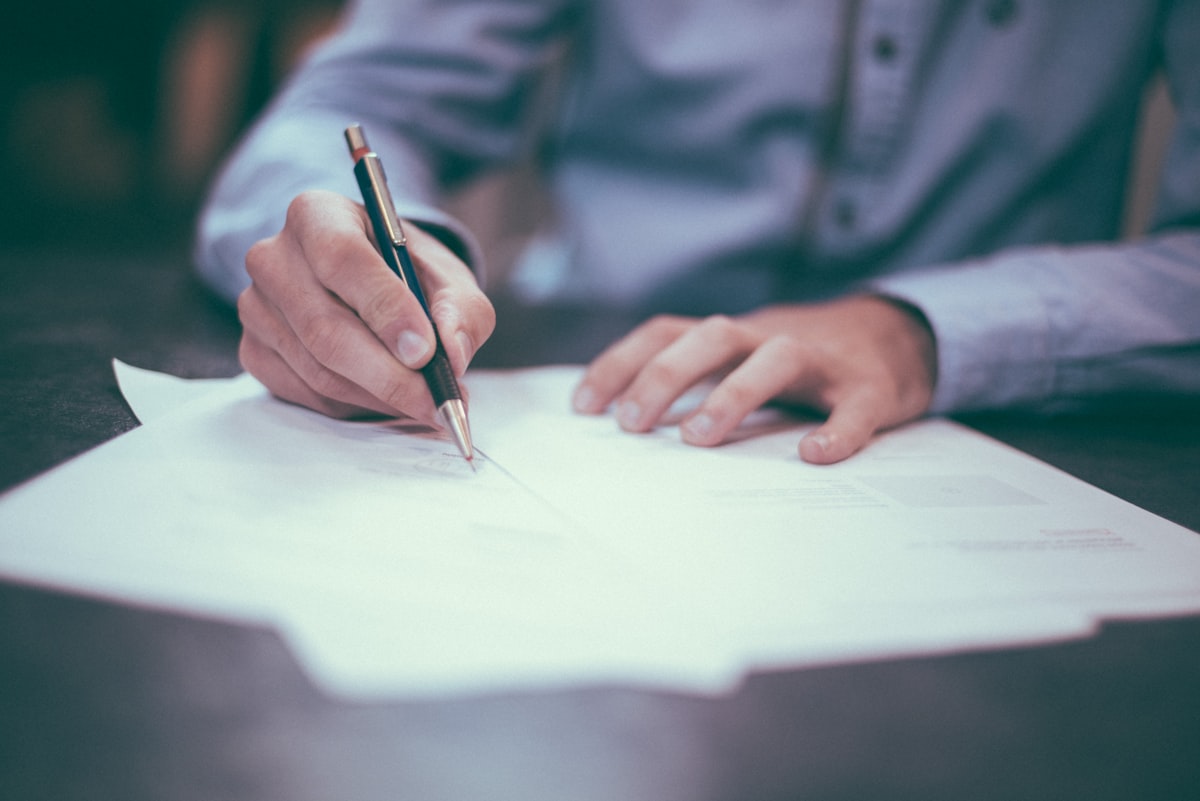 Person reviewing financial documents and calculations at a desk, representing property price analysis for clients