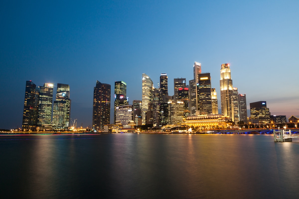 Singapore CBD skyline at dusk with Raffles Place Grade A office towers reflected in Marina Bay water