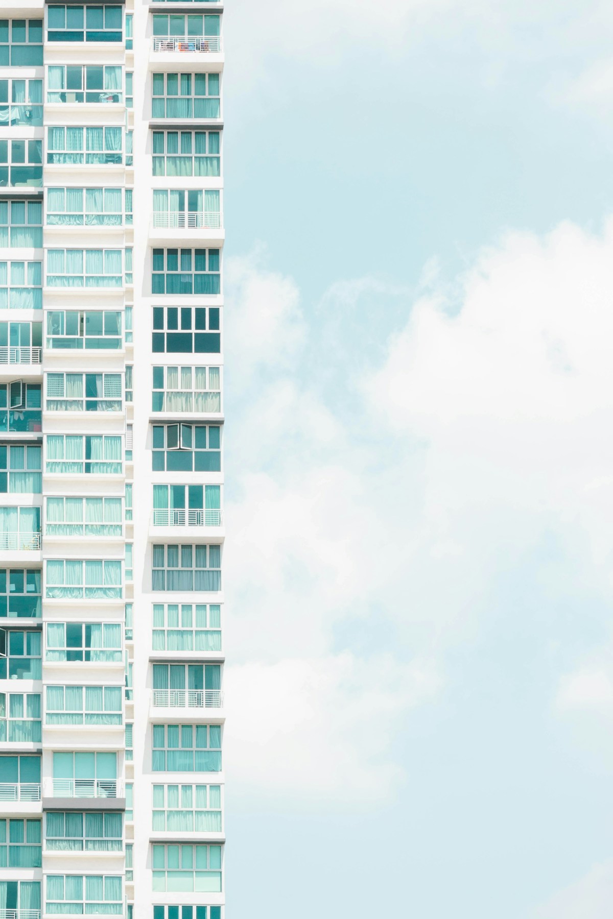 Close-up of a modern Singapore residential condo facade with glass balconies, illustrating the newer end of the two-tier residential market