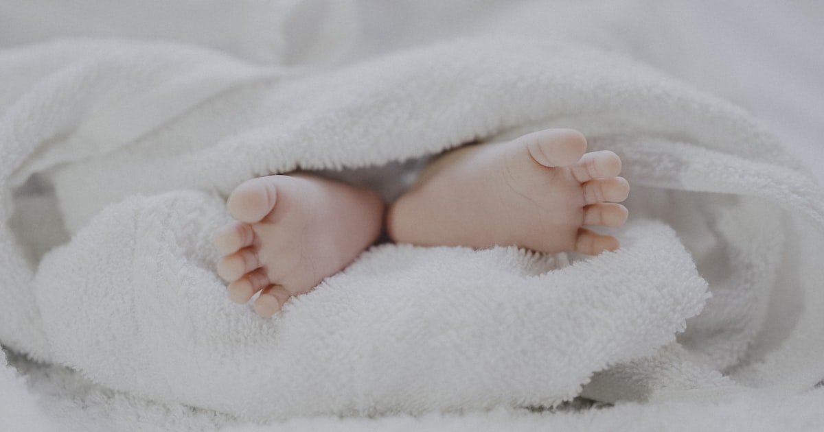Newborn baby feet wrapped in a white blanket representing Singapore's record-low birth rate